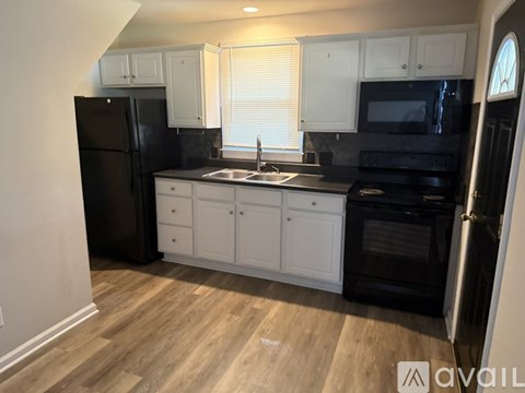 A kitchen with black appliances and white cabinets.
