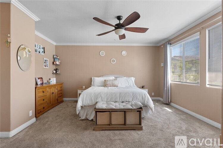A bedroom with a bed, dresser, and ceiling fan.