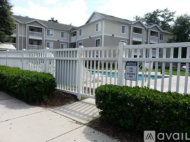 A white fence surrounds a pool with a sign that says "NOTICE Residents Only".