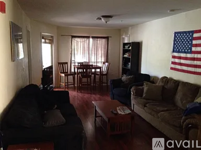 A living room with a black couch, a brown couch, a coffee table, and an American flag hanging on the wall.