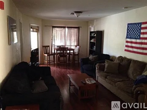 A living room with a black couch, a brown couch, a coffee table, and an American flag hanging on the wall.
