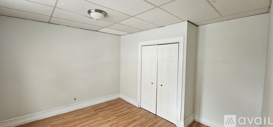 A room with a white door and wooden flooring.