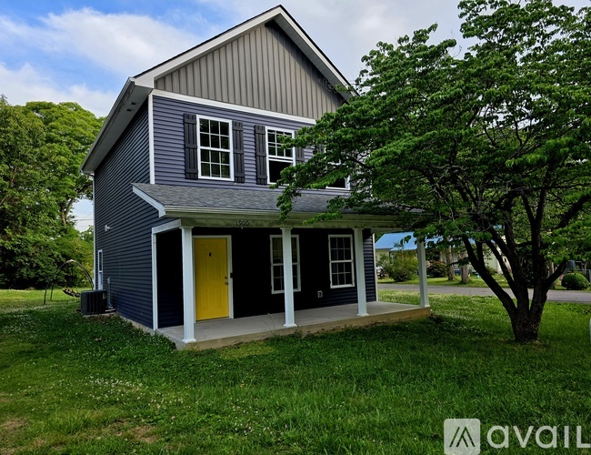 A house with a grey exterior and a yellow door.