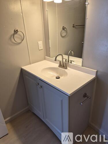 A bathroom sink with a white counter top and a cabinet below it.