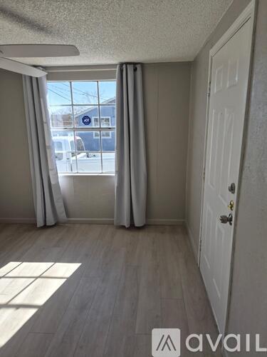 A room with a white door and a window with curtains.