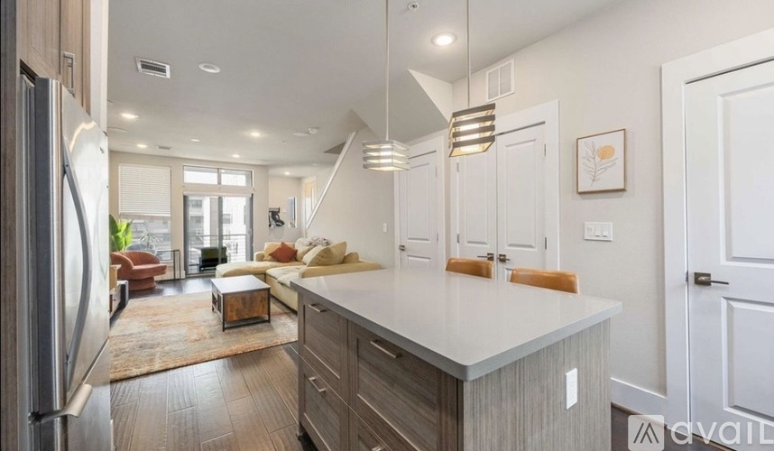 A modern kitchen with a refrigerator on the left and a dining area in the background.