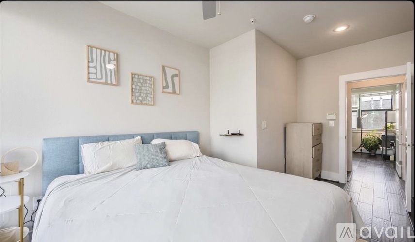 A bedroom with a large bed and a small table with a lamp.