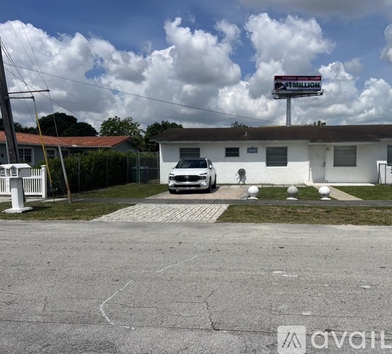 A white car is parked in front of a house with a billboard that says "1 Million".