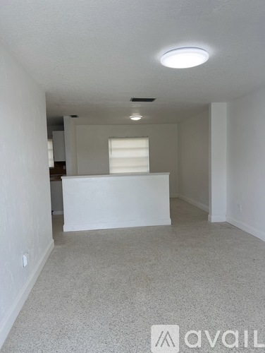 A white room with a light on the ceiling and a window with blinds.