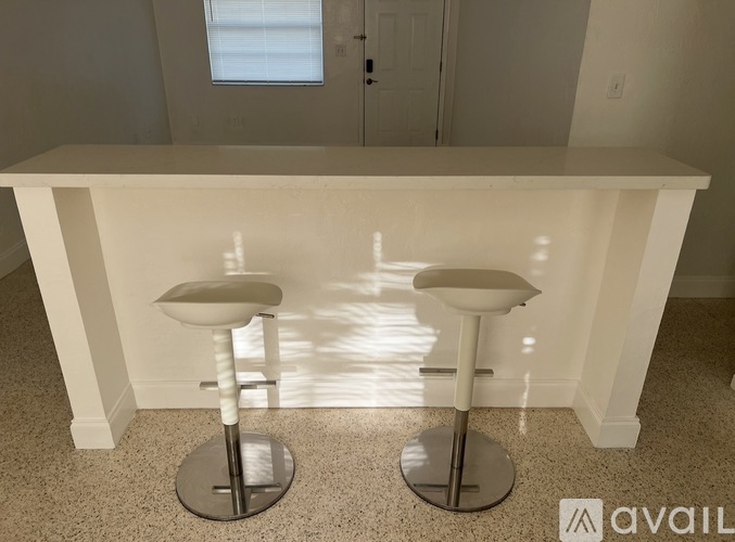 Two white stools are placed in front of a white counter.