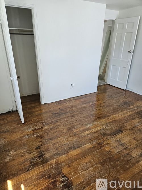 A room with wooden floors and two white doors.