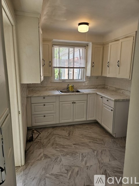 A kitchen with a marble floor and white cabinets.