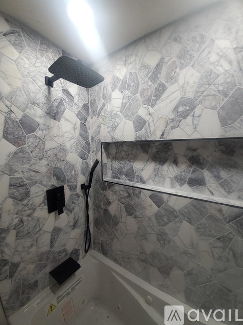 A bathroom with a shower head and a tiled wall.