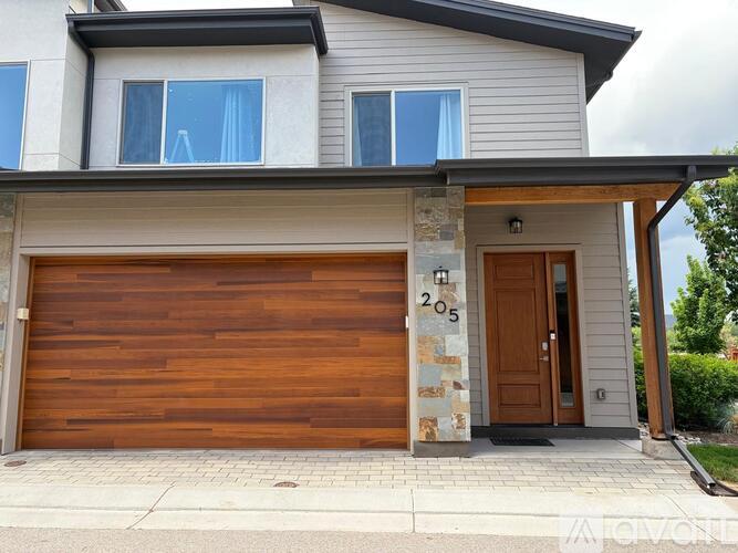 A modern house with a wooden garage door and a stone pillar.