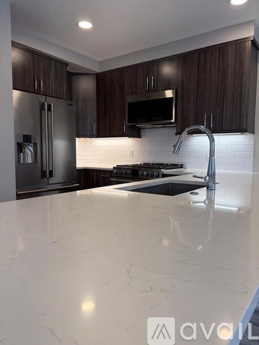 A kitchen with a white countertop and dark brown cabinets.