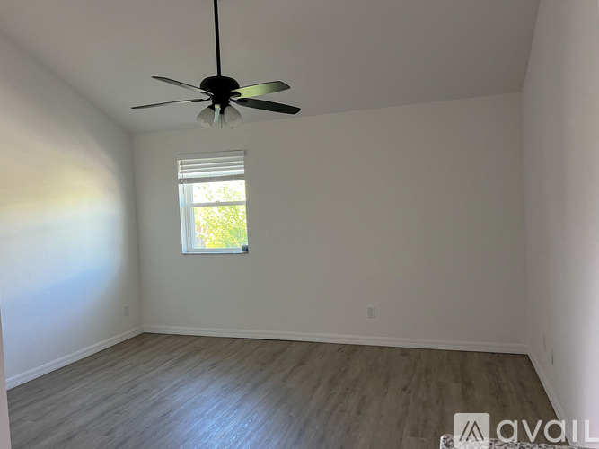 A room with a ceiling fan and a window letting in light.