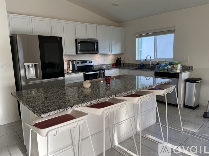 A kitchen with granite countertops and white chairs.