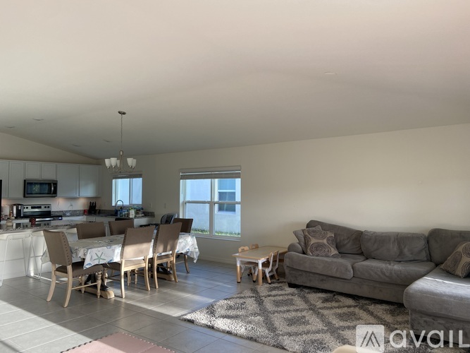 A living room with a grey couch and a dining table with chairs.