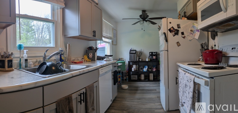A kitchen with a sink, refrigerator, and a fan.