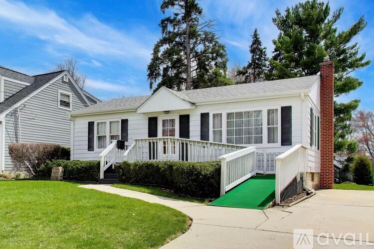 A house with a white exterior and a green ramp leading to the front door.