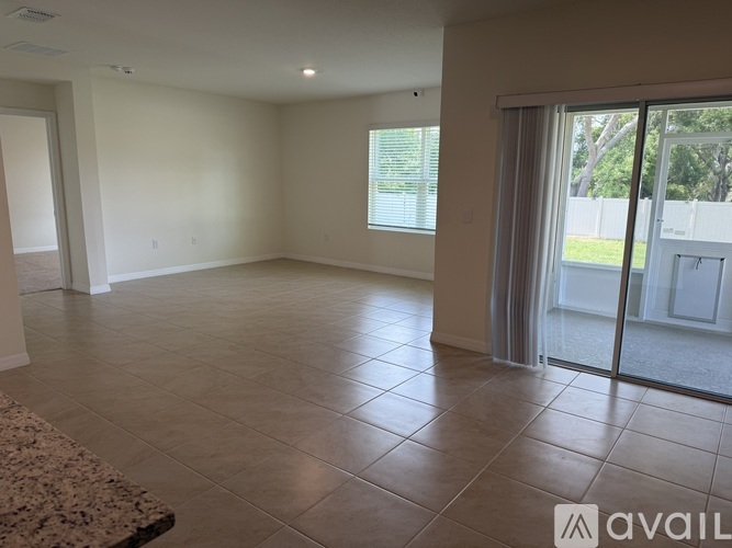 A spacious room with tiled flooring and sliding glass doors leading to a backyard.