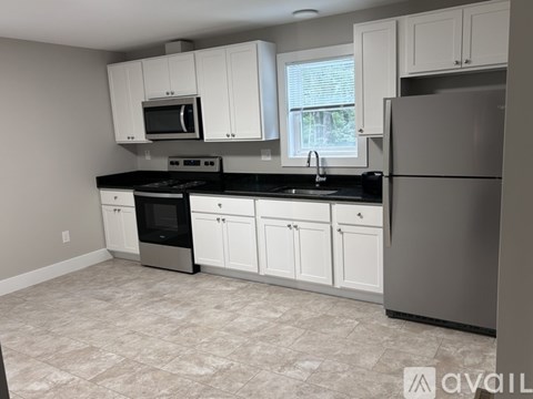 A kitchen with white cabinets and black countertops.