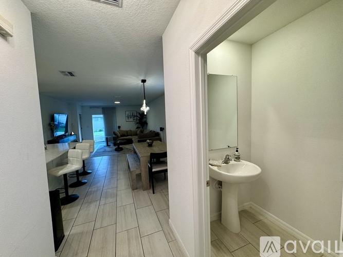 A bathroom with a sink and mirror in the foreground and a dining area in the background.