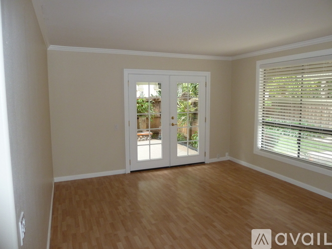 A room with wooden floors and a large window with blinds.