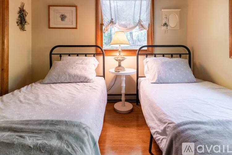 Two twin beds are in a room with a window and a wall hanging.