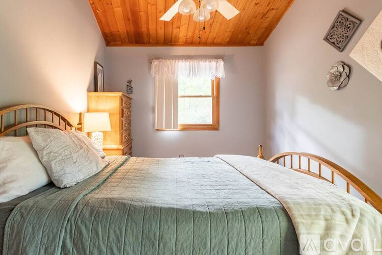 A bedroom with a bed, a window, and a ceiling fan.