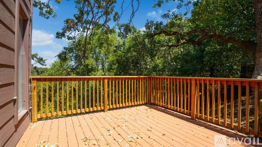 A wooden deck with a railing and trees in the background.
