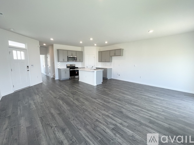 A spacious room with wooden flooring and white walls.