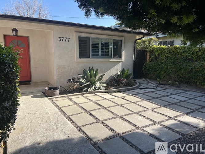 A house with the number 3777 on it has a red door and a red window.