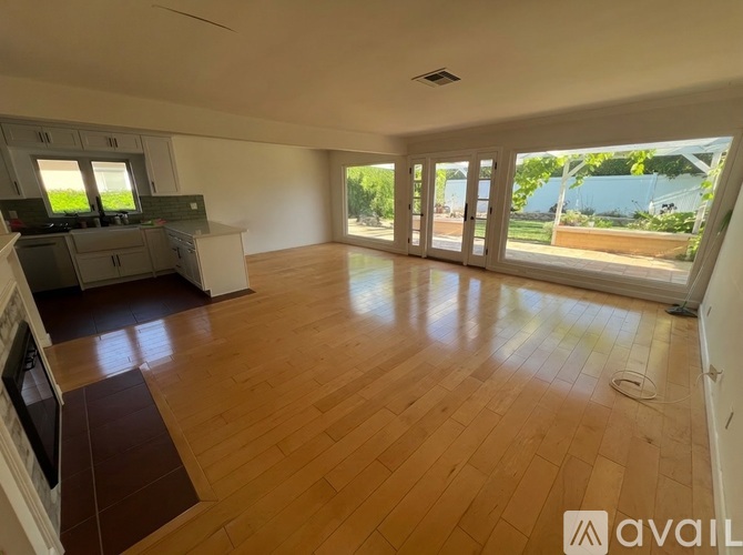 A spacious room with wooden flooring and large windows.