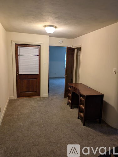 A room with a desk and a door leading to a blue room.