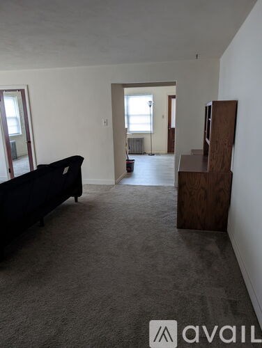 A living room with a black couch and a wooden cabinet.