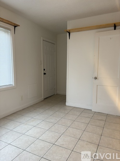 A room with white walls and a tiled floor with two doors.
