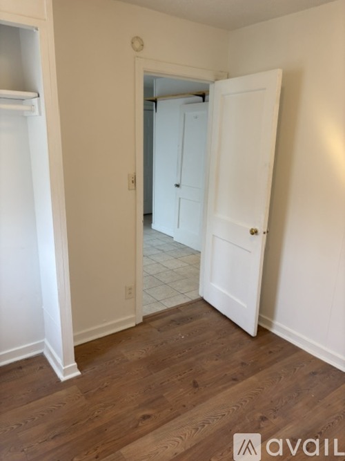 A room with a white door and wooden flooring.