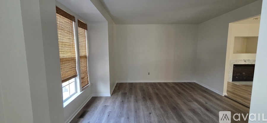 A room with wooden floors and a window with blinds.