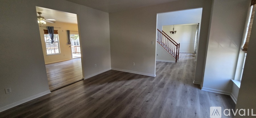 A spacious room with wooden floors and a staircase leading to another room.