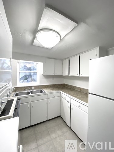 A kitchen with white cabinets and a skylight.