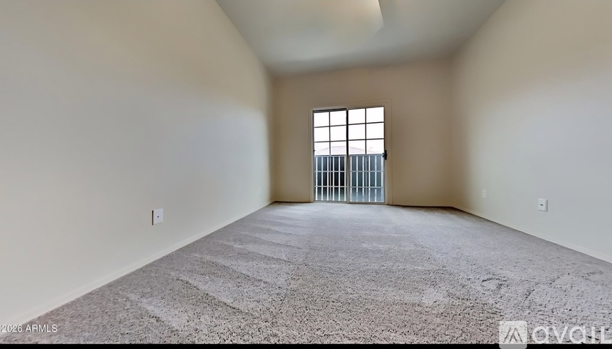 A spacious room with a carpeted floor and a window with bars on it.