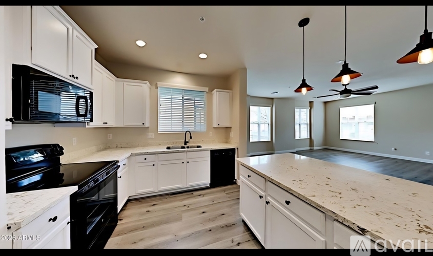 A kitchen with white cabinets and a black microwave.