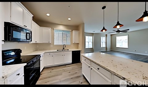 A kitchen with white cabinets and a black microwave.
