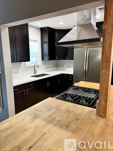 A kitchen with a wooden table in the foreground and black cabinets.