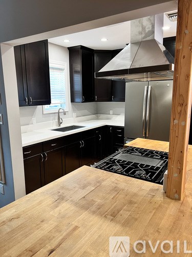 A kitchen with a wooden table in the foreground and black cabinets.