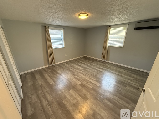 A room with wooden flooring and a window with blinds.