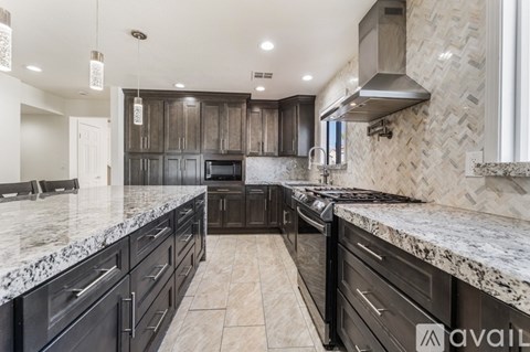 A kitchen with black cabinets and a marble countertop.