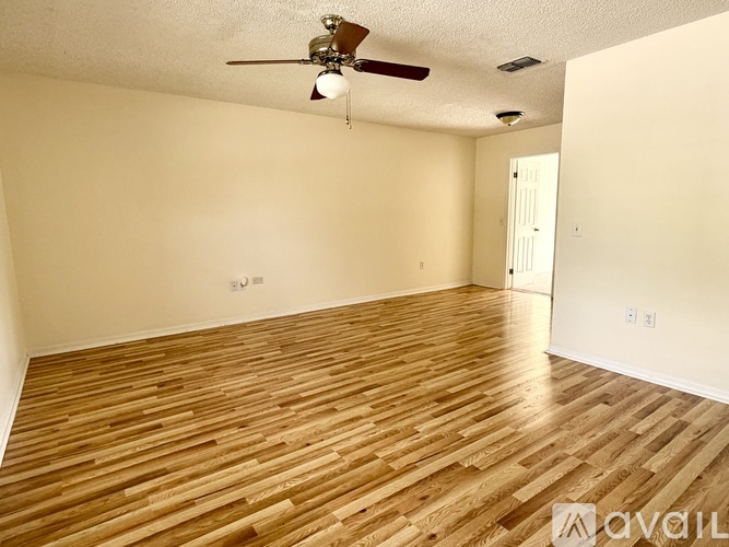 A room with wooden flooring and a ceiling fan.