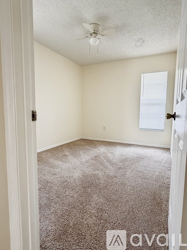 A room with a carpeted floor and a ceiling fan.